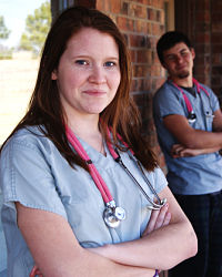 Female and Male Nurse standing outside of building and smiling