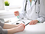 A female is sitting down at a desk across from a female Nurse