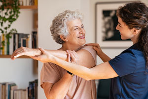 Older female patient being assisted by a female Nurse during a physical therapy session.